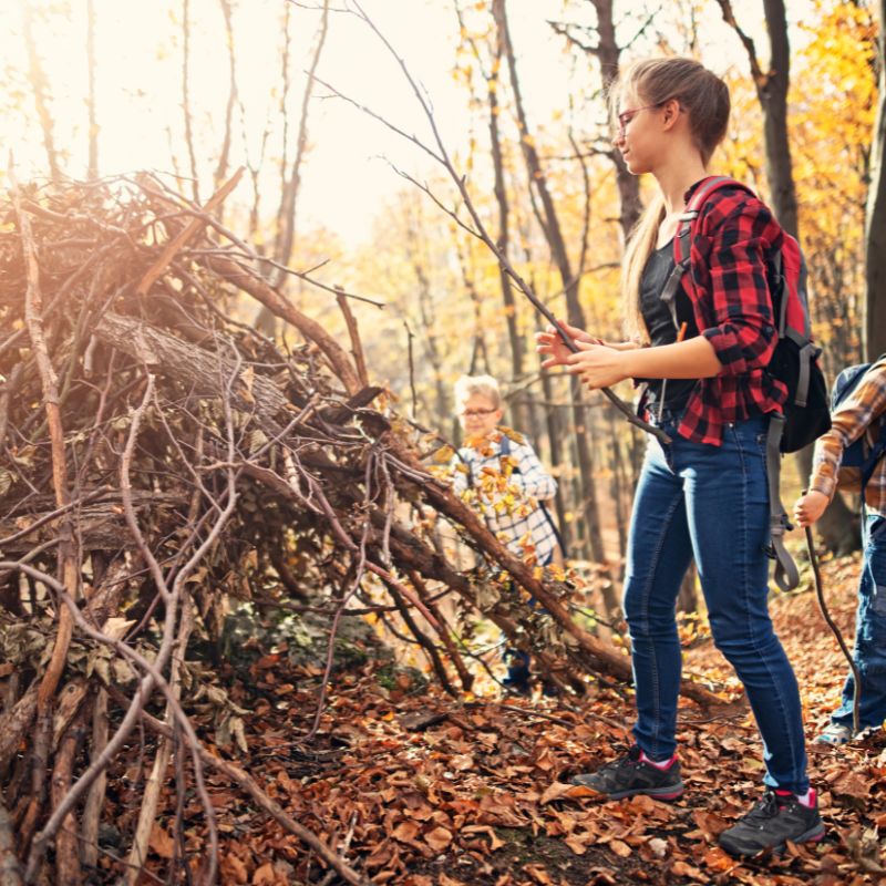 enfant qui s'amuse dans les bois en construisant une cabane