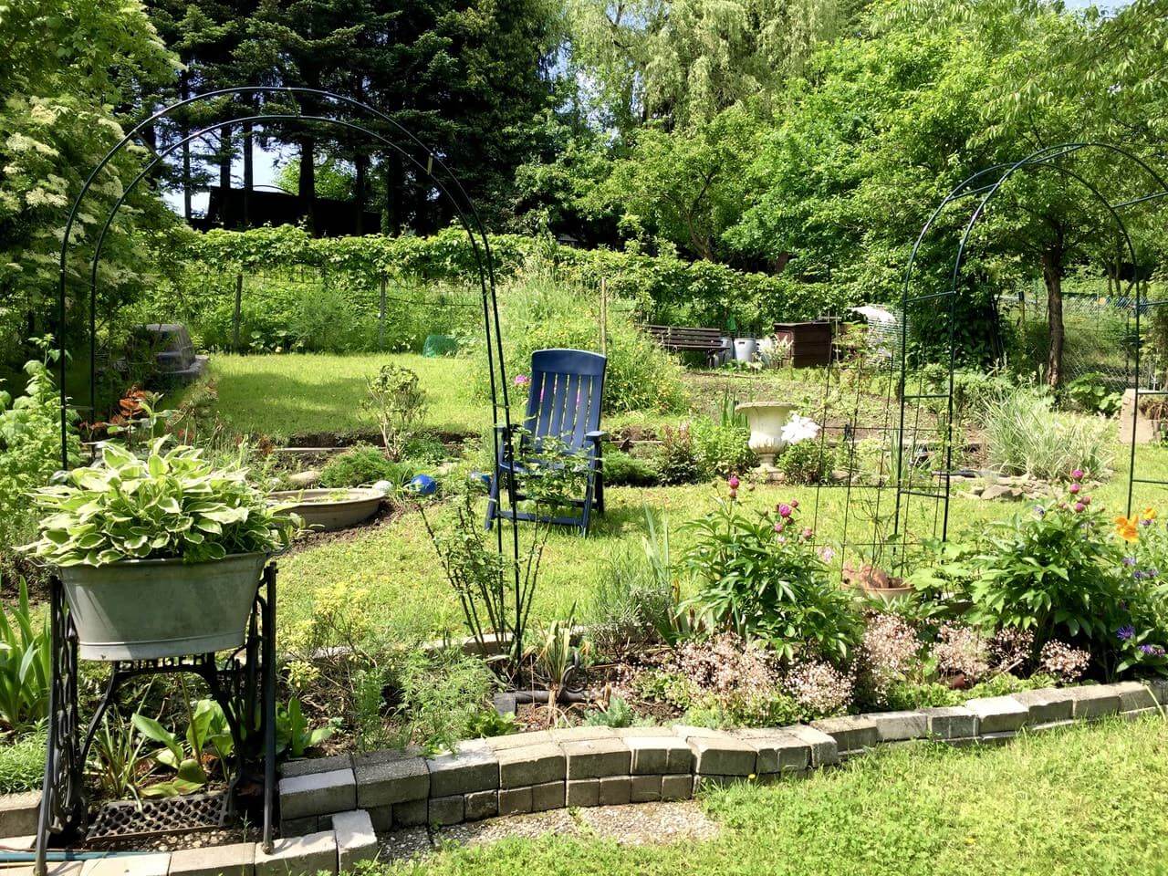 jardin anglais à plusieurs niveaux avec potiches de fleurs et chaise de jardin